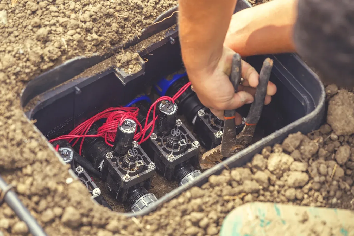 Irrigation valve box opened for repair beside a lawn