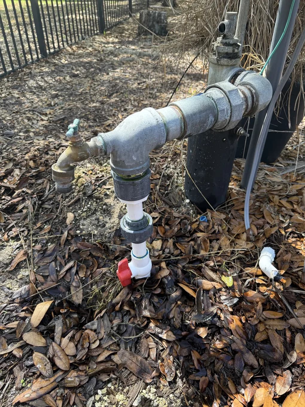 Irrigation well head plumbing with galvanized fittings, a hose bib and a red shut-off valve