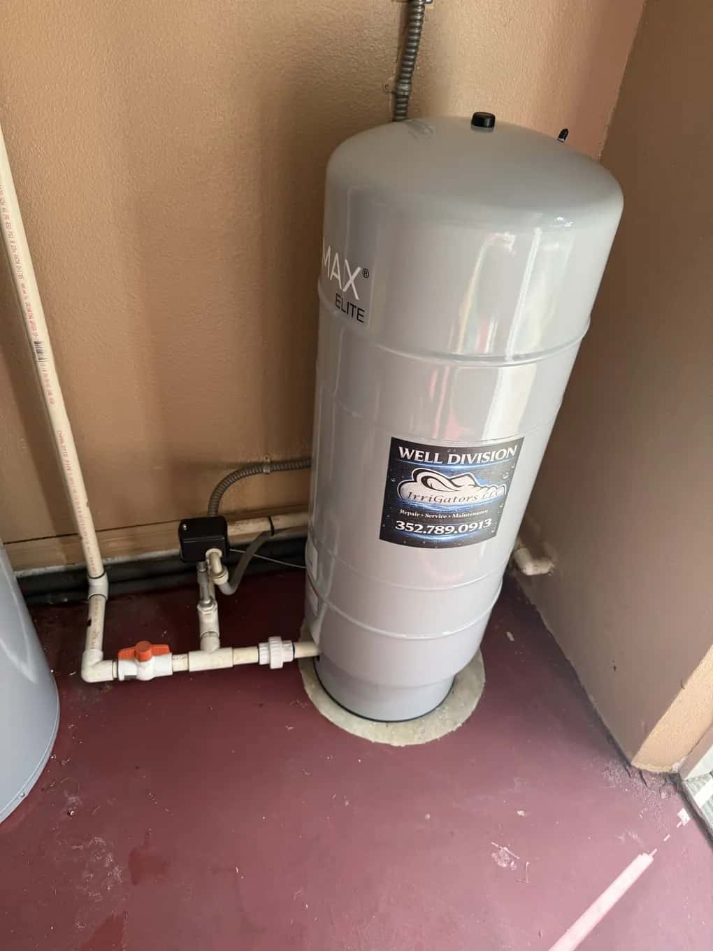 Pressure tank with an IrriGators Well Division label installed in a utility closet