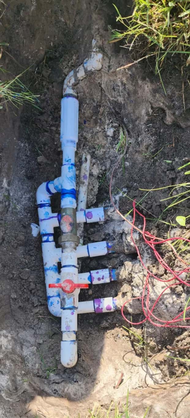 Newly built sprinkler valve manifold with four zone outlets, a brass fitting and a red shut-off valve