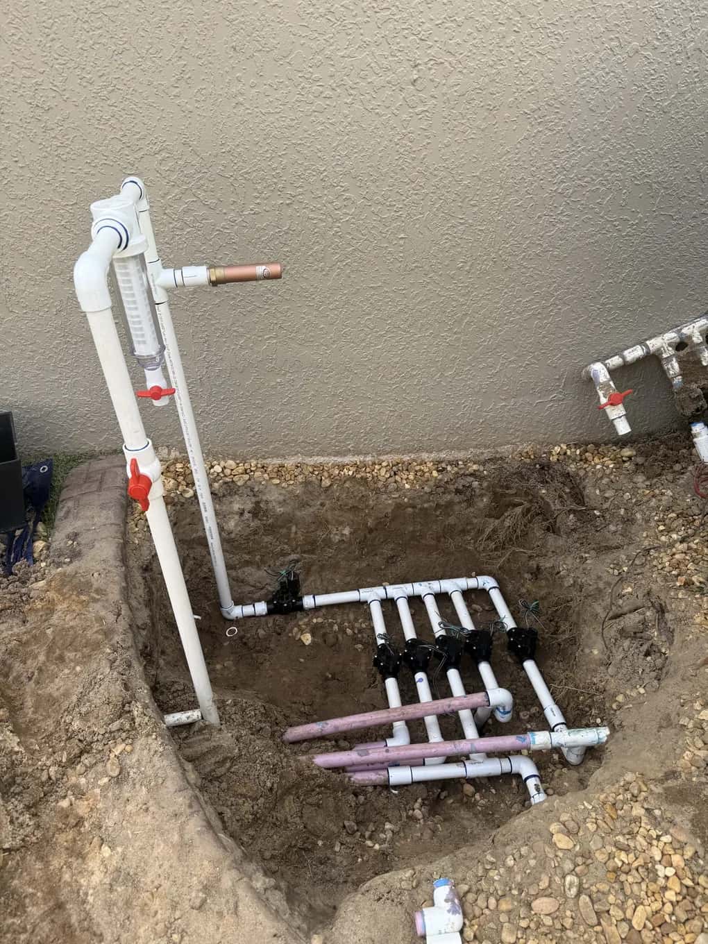 New five-zone sprinkler valve manifold with a backflow riser, installed beside a house
