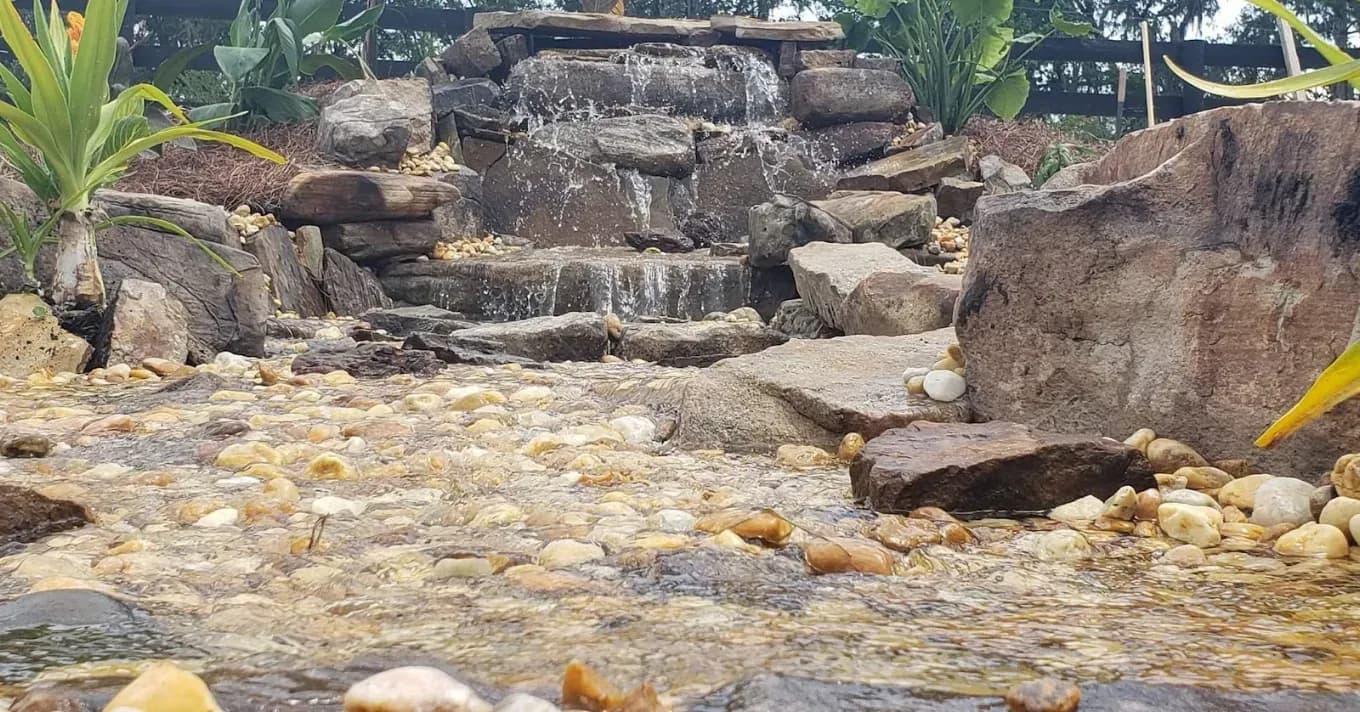 Rock waterfall water feature set into a landscaped yard