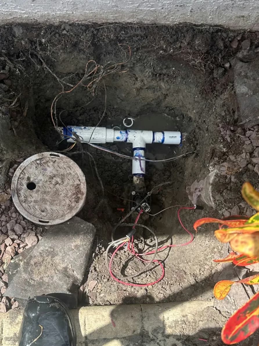 Sprinkler valve repair with new PVC tee fittings beside an open valve box