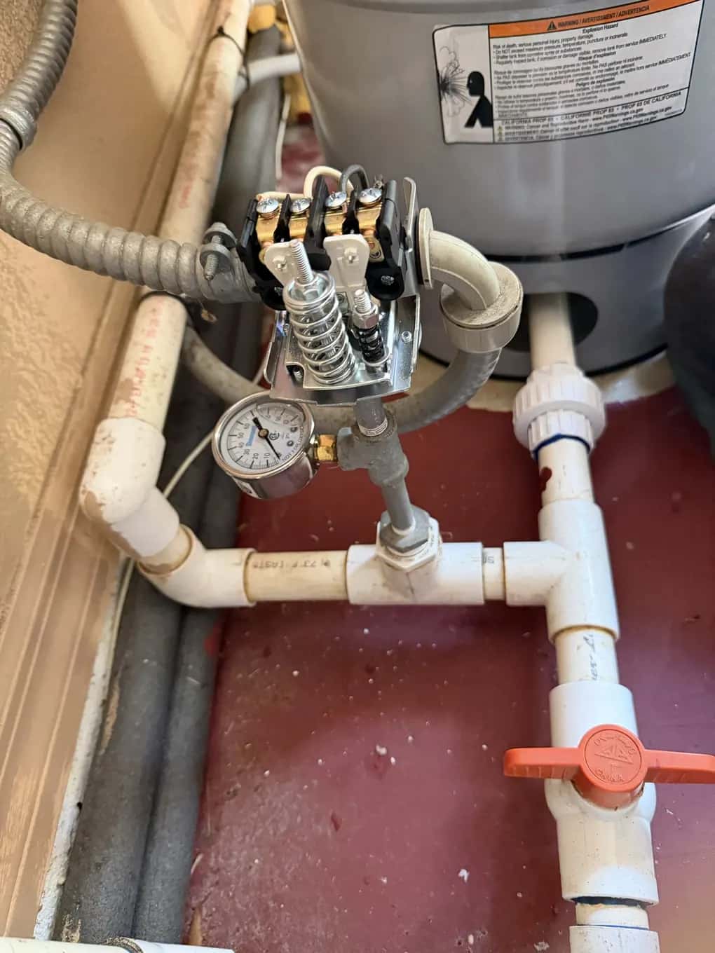 Well pump pressure switch and pressure gauge on the tank tee beside a pressure tank